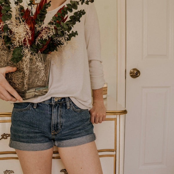 woman holding vase with red petaled flower