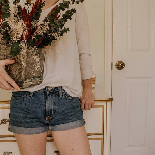 woman holding vase with red petaled flower