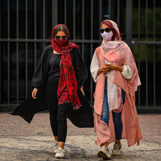 woman in red hijab and black dress standing on brown sand during daytime