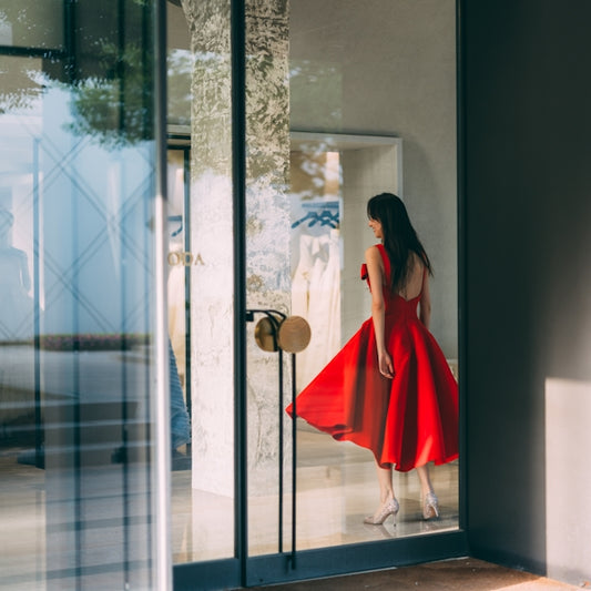 woman in red dress standing in front of glass door