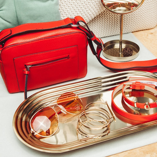 a silver tray with a red purse and other items